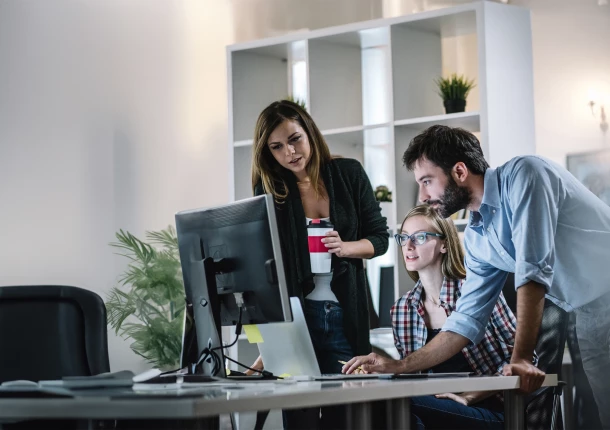 mehrere Personen schauen interessiert auf einen Bildschirm 