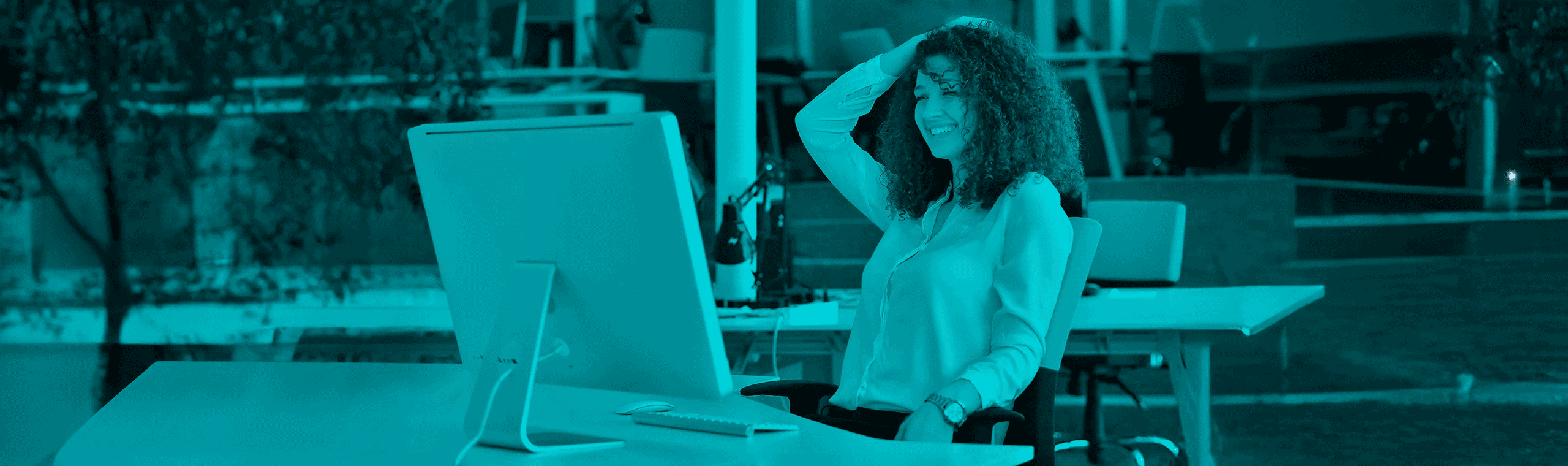 Frau im Büro, die lächelnd vor einem Computer sitzt – Symbolbild für erfolgreiches Prompting in der KI-gestützten Content-Erstellung.