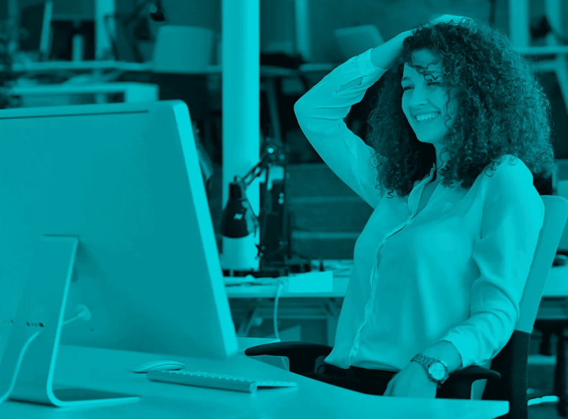 Frau im Büro, die lächelnd vor einem Computer sitzt – Symbolbild für erfolgreiches Prompting in der KI-gestützten Content-Erstellung.